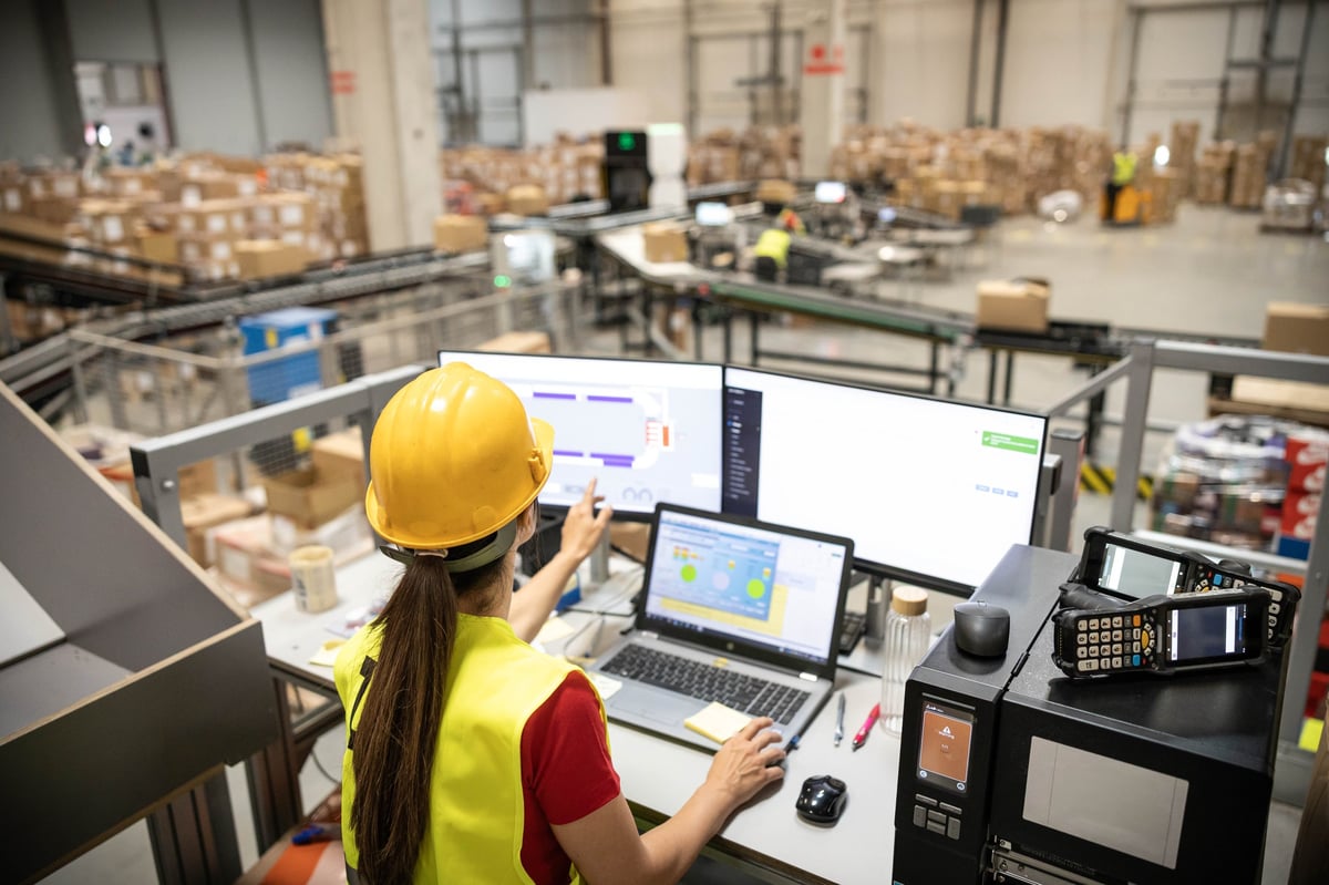 Woman analyzing real-time data on computer within a warehouse